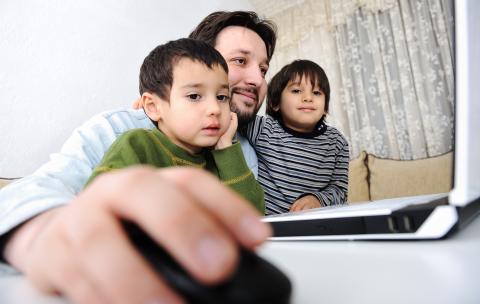 Fifteen Years of Working and Schooling From Home man working on laptop with two children